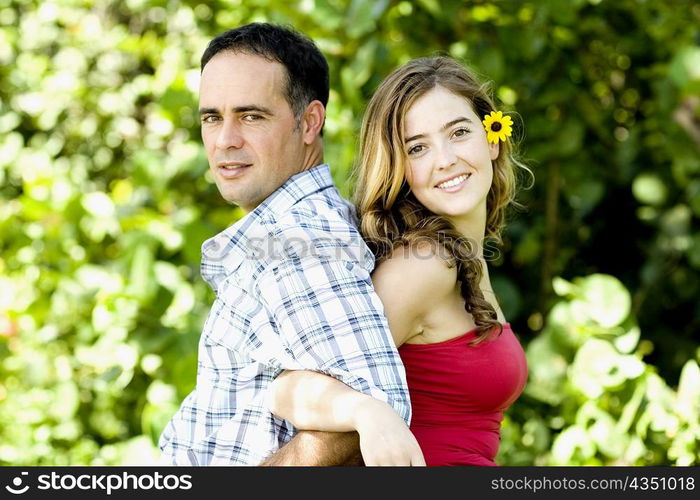 Side profile of a young woman and a mid adult man standing back to back