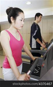 Side profile of a young woman and a young man exercising in a gym
