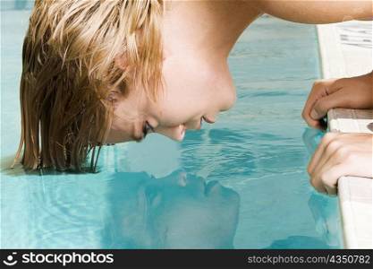 Side profile of a young woman bending forward with her hair in a swimming pool