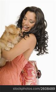 Side profile of a young woman carrying a Pomeranian dog and smiling
