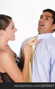 Side profile of a young woman choking a mid adult man with his tie