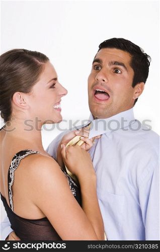 Side profile of a young woman choking a mid adult man with his tie