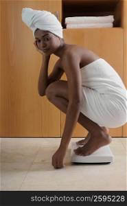 Side profile of a young woman crouching on a weighting scale