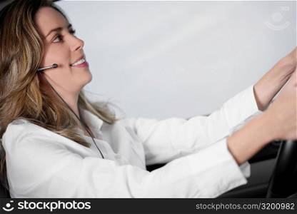 Side profile of a young woman driving a car and wearing a hands free device