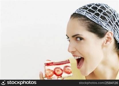 Side profile of a young woman eating a slice of strawberry cake
