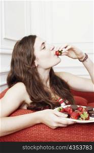 Side profile of a young woman eating a strawberry