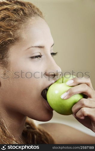 Side profile of a young woman eating an apple