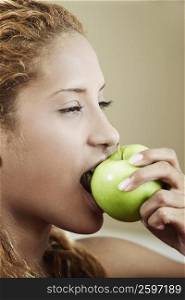 Side profile of a young woman eating an apple