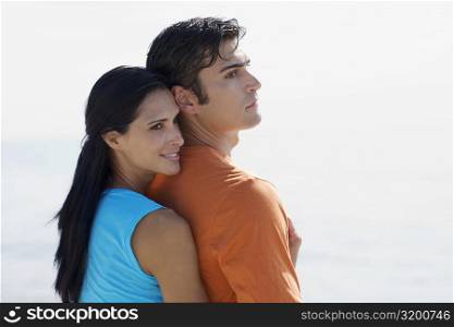 Side profile of a young woman embracing a mid adult man from behind