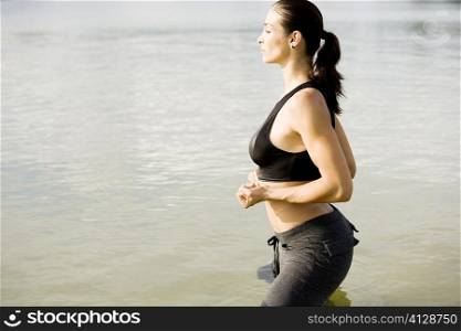 Side profile of a young woman exercising in a lake