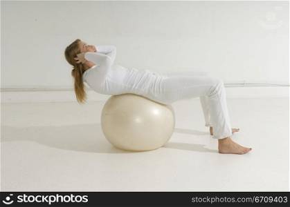 Side profile of a young woman exercising on a fitness ball