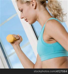 Side profile of a young woman exercising with a dumbbell