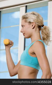 Side profile of a young woman exercising with dumbbells