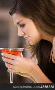 Side profile of a young woman holding a glass of martini