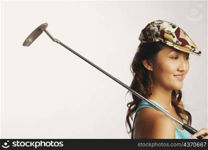 Side profile of a young woman holding a golf club and looking down