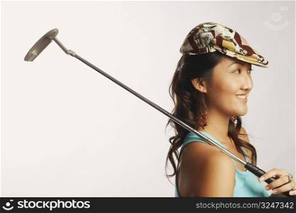 Side profile of a young woman holding a golf club and smiling