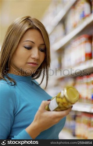 Side profile of a young woman holding a jar of pickle