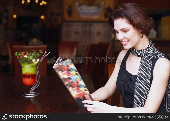 Side profile of a young woman holding a menu card in a restaurant