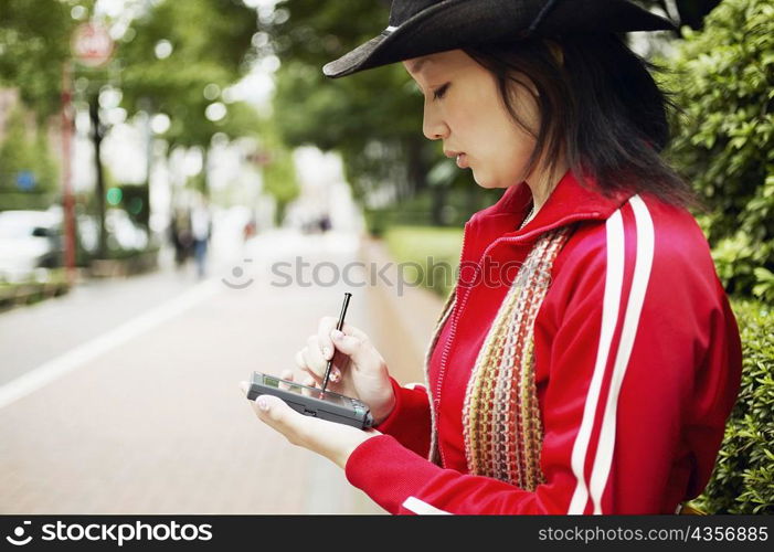 Side profile of a young woman holding a personal data assistant