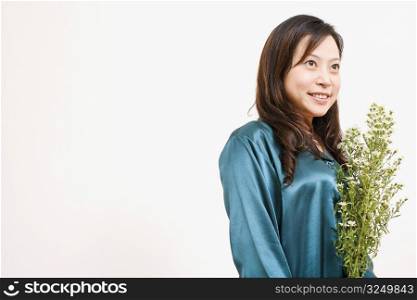 Side profile of a young woman holding a plant and smiling
