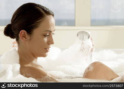 Side profile of a young woman holding a shower head