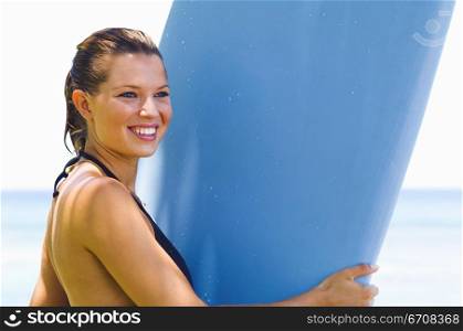 Side profile of a young woman holding a surfboard