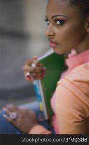 Side profile of a young woman holding a textbook