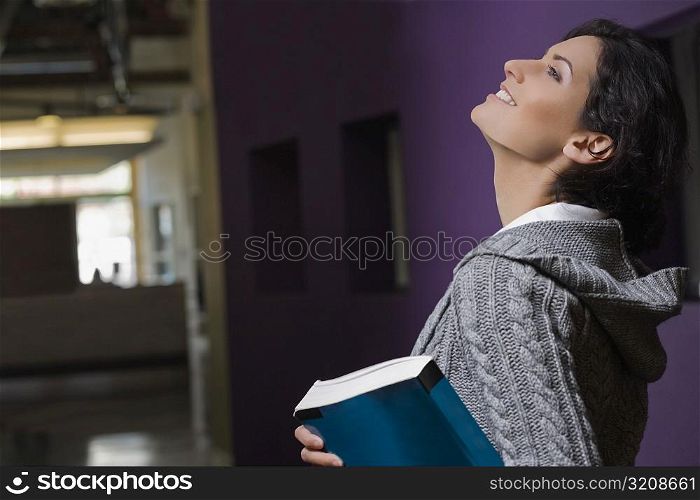 Side profile of a young woman holding a textbook