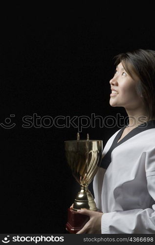 Side profile of a young woman holding a trophy