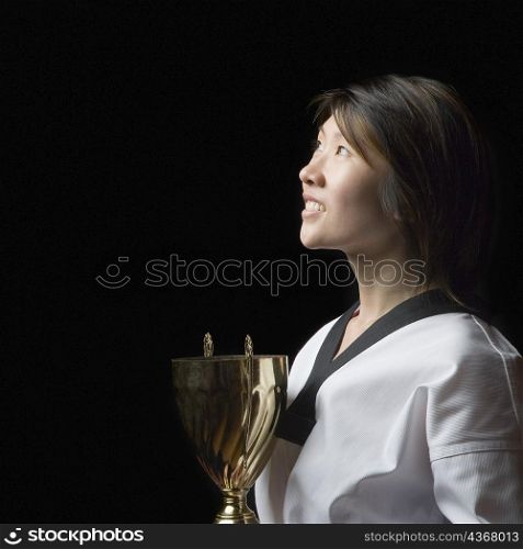 Side profile of a young woman holding a trophy