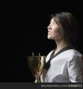 Side profile of a young woman holding a trophy