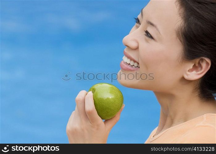 Side profile of a young woman holding an green apple