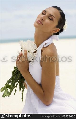 Side profile of a young woman holding flowers on the beach
