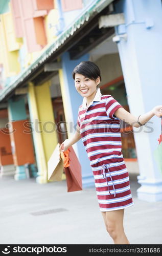 Side profile of a young woman holding shopping bags and smiling
