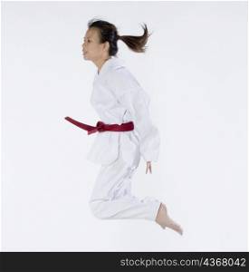 Side profile of a young woman jumping and practicing martial arts