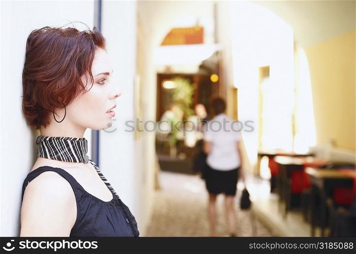 Side profile of a young woman leaning against a wall