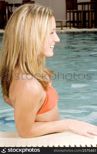 Side profile of a young woman leaning at the edge of a swimming pool