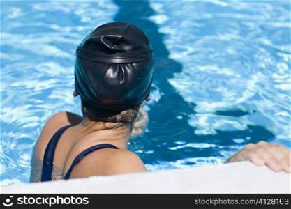 Side profile of a young woman leaning at the ledge of a swimming pool