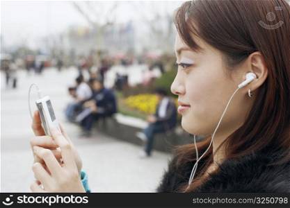 Side profile of a young woman listening at an MP3 player