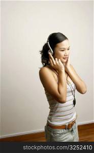 Side profile of a young woman listening to music and holding a mobile phone