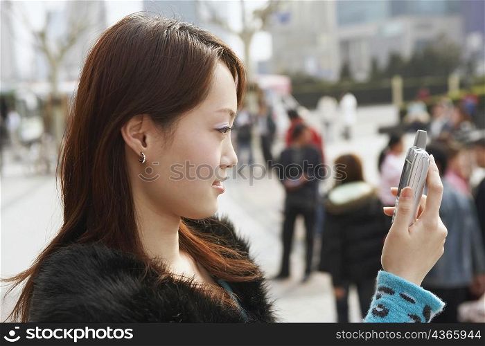 Side profile of a young woman looking at a mobile phone