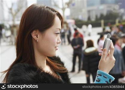 Side profile of a young woman looking at a mobile phone