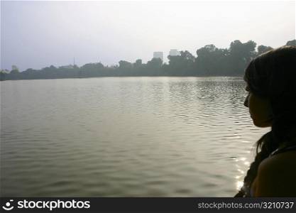 Side profile of a young woman looking in river, Hanoi, Vietnam