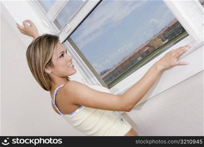 Side profile of a young woman looking through a window and smiling