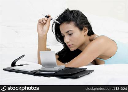Side profile of a young woman lying on a bed in front of a personal organizer