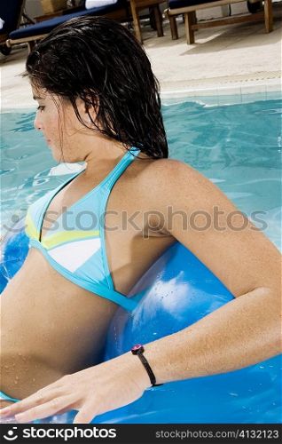 Side profile of a young woman lying on an inflatable chair in a swimming pool