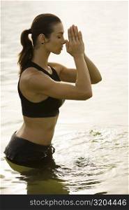 Side profile of a young woman meditating in a lake