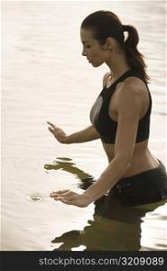 Side profile of a young woman meditating in a lake