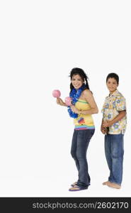 Side profile of a young woman playing maracas and a boy playing ukulele