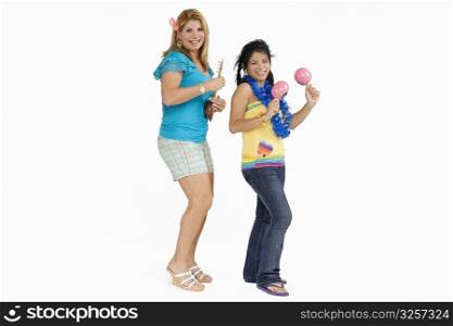 Side profile of a young woman playing maracas and her mother playing ukulele